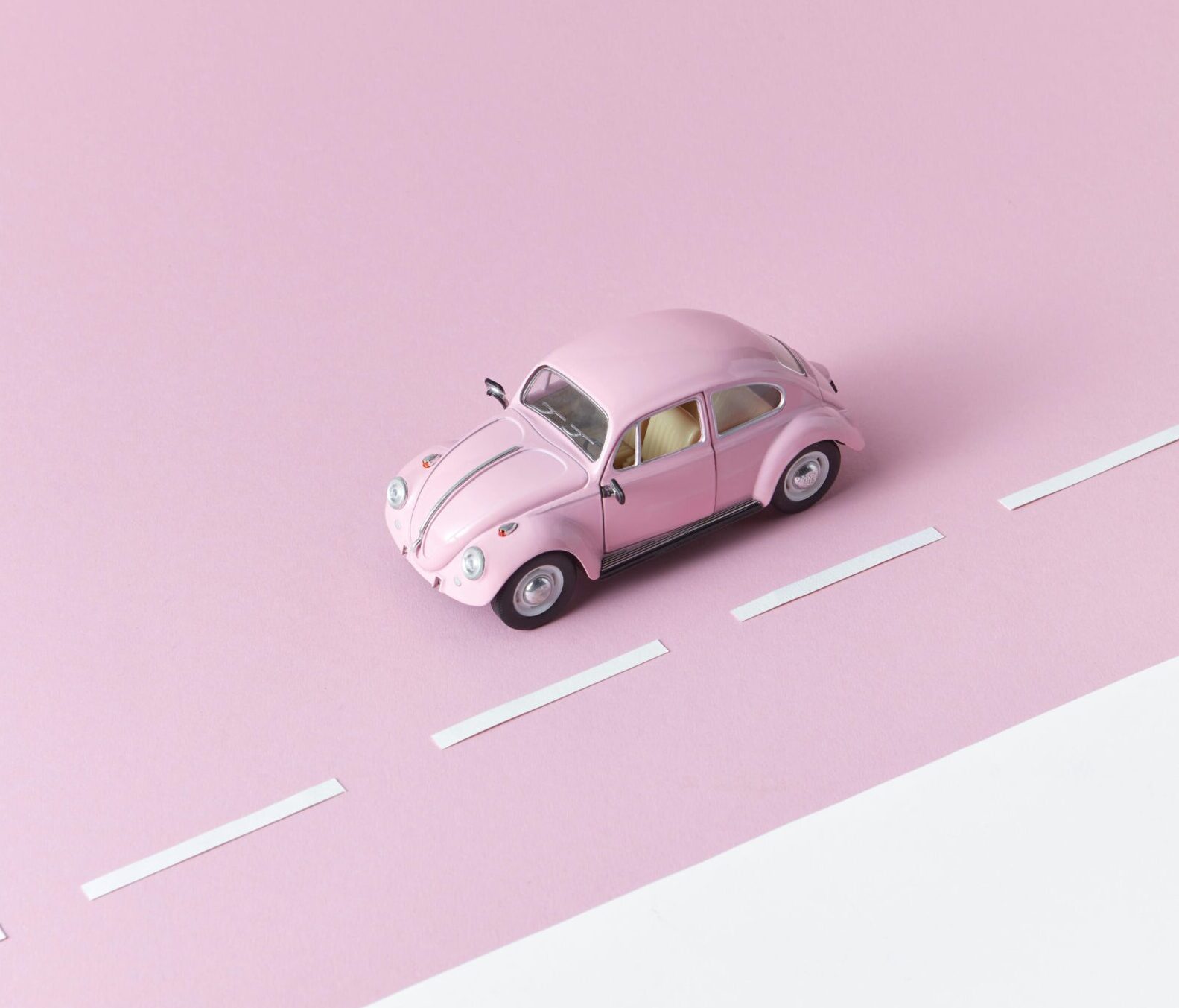 A pink toy car on a minimalistic pastel pink surface, representing simplicity and playfulness.